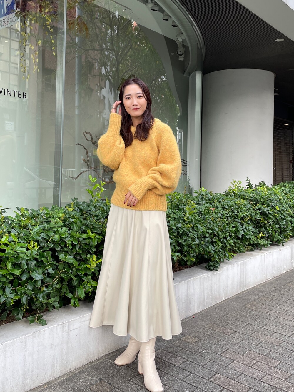ホワイト系のブーツ、ホワイト系のスカート、イエロー系のニット/セーターを着用したレディースの秋コーディネートの3枚目の写真