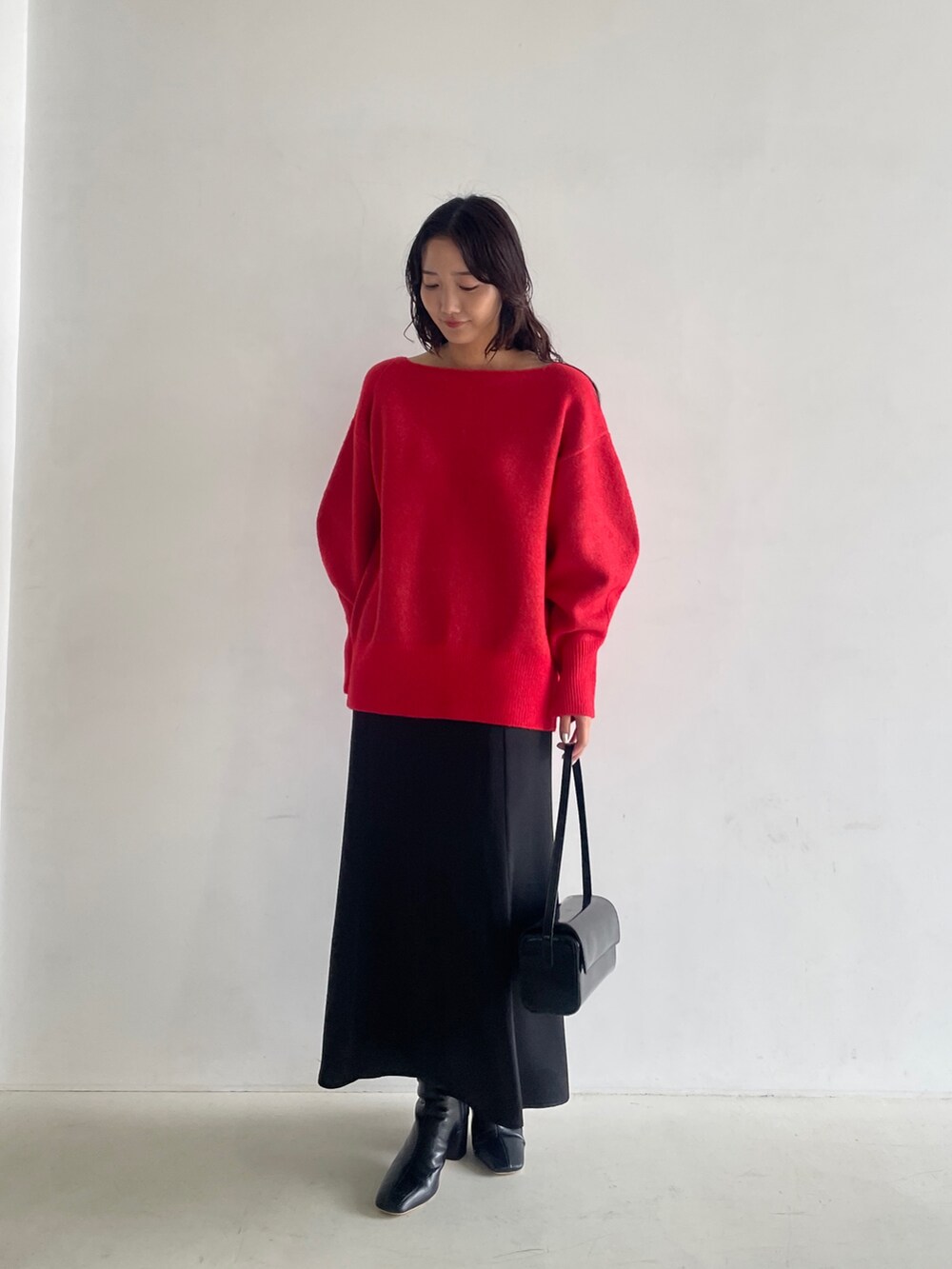 ブラック系のブーツ、ブラック系のスカート、レッド系のニット/セーターを着用したレディースの秋コーディネートの2枚目の写真