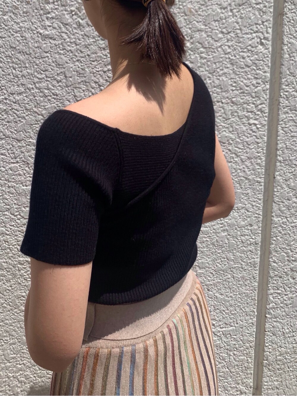 ベージュ系のスカート、ブラック系のニット/セーター、ゴールド系のバングル/リストバンドを着用したレディースの春コーディネートの5枚目の写真