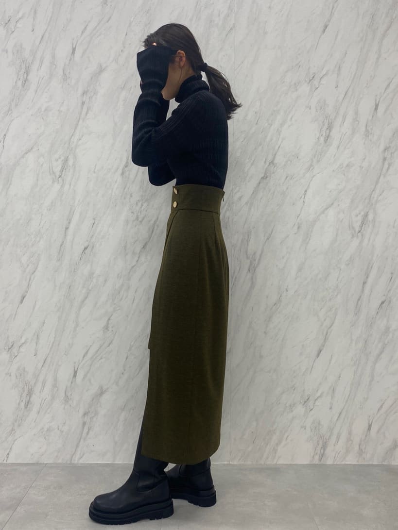 ベージュ系のスカート、ブラック系のニット/セーター、ブラック系のブーツを着用したレディースの夏コーディネートの5枚目の写真