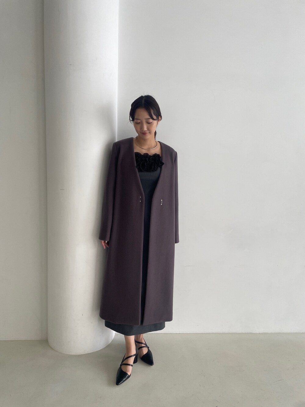 グレー系のドレス、ブラック系のパンプス、グレー系のチェスターコートを着用したレディースの秋コーディネートの3枚目の写真