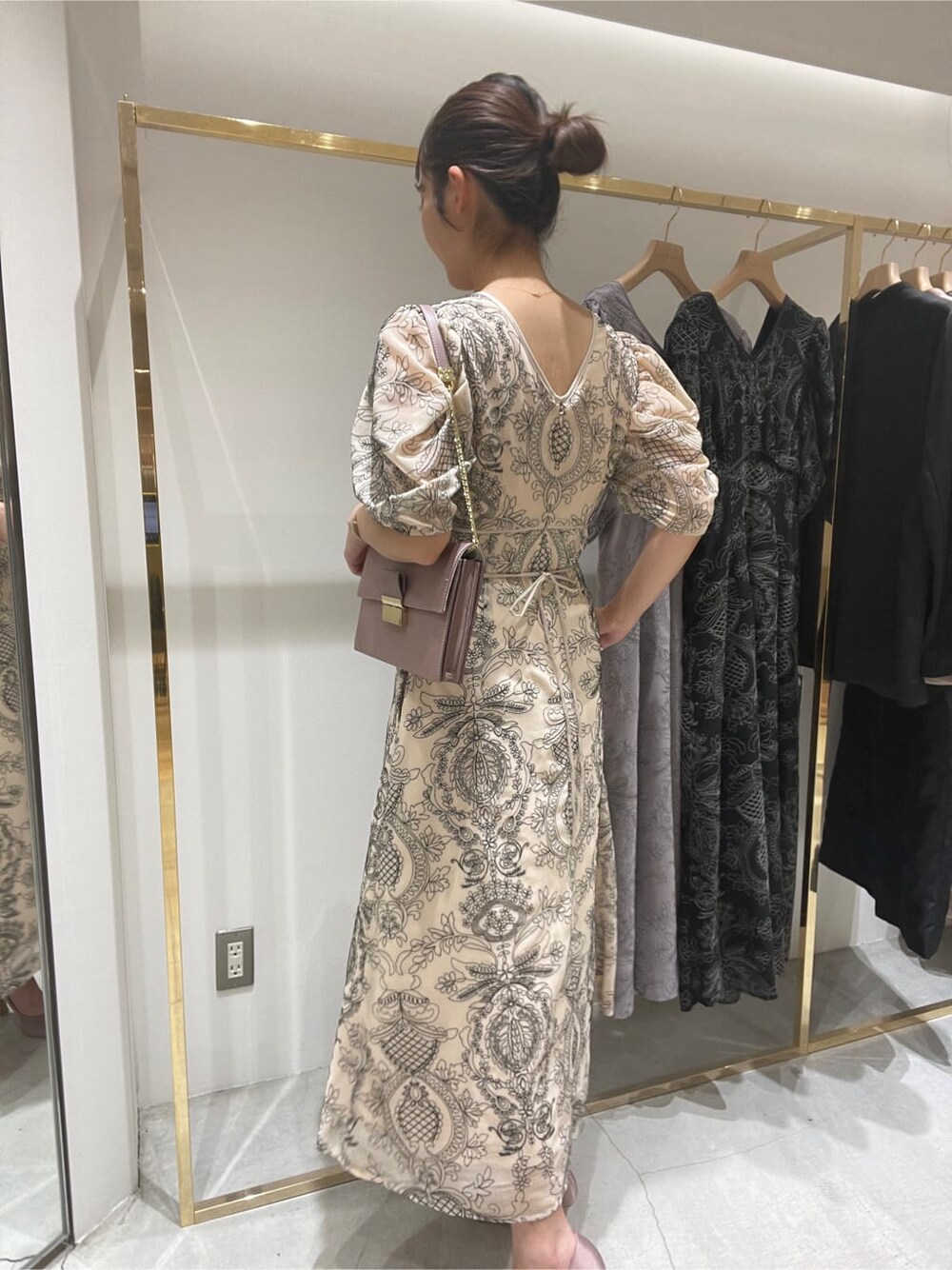 ベージュ系のドレス、ピンク系のパンプス、ピンク系のクラッチバッグを着用したレディースの春コーディネートの4枚目の写真