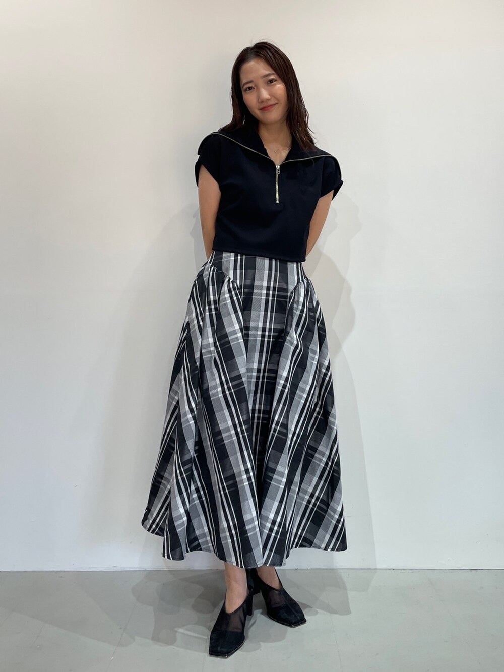 ブラック系のTシャツ/カットソー、ブラック系のパンプス、ホワイト系のスカートを着用したレディースの夏コーディネートの2枚目の写真