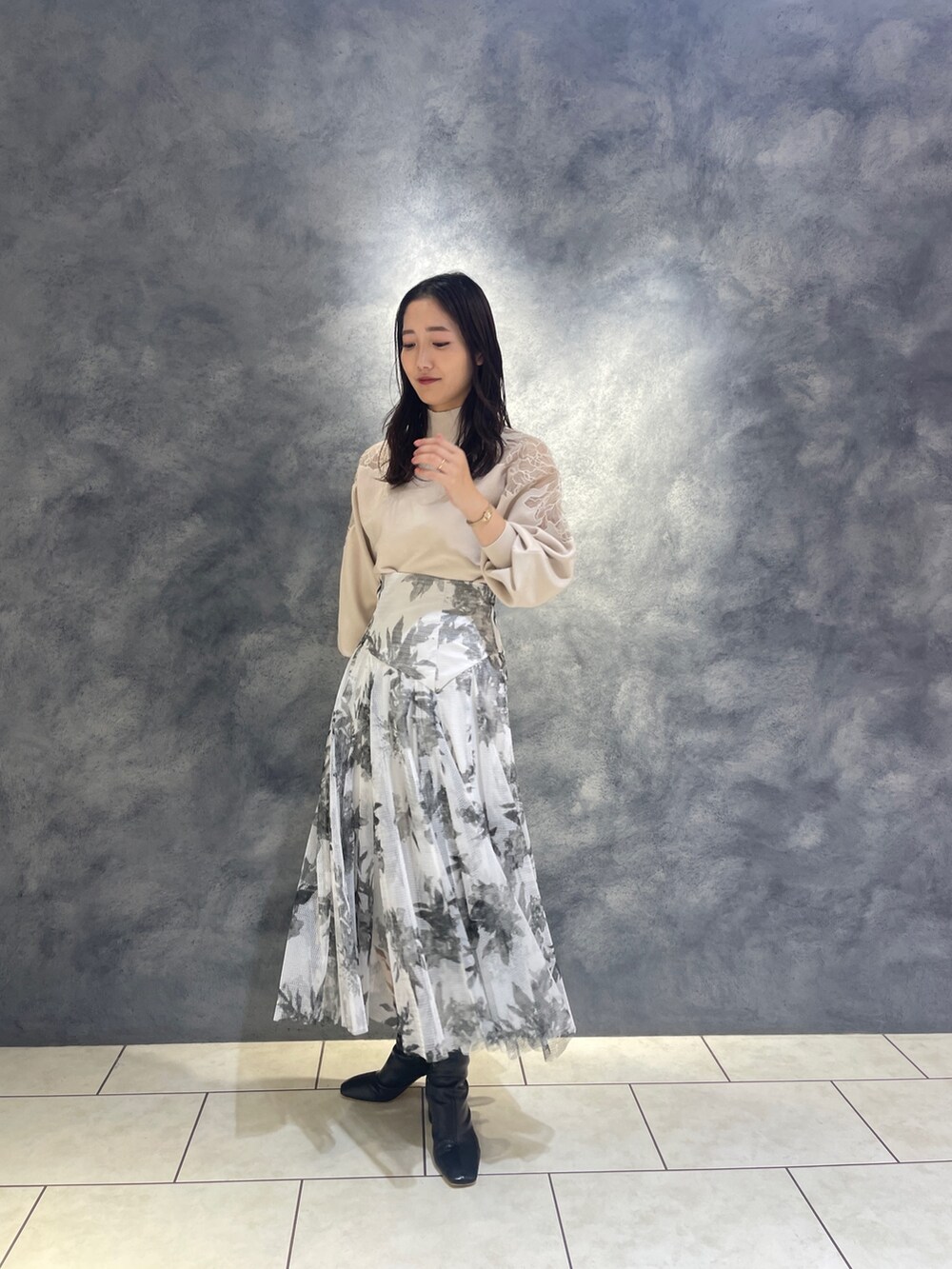 ホワイト系のニット/セーター、ブラック系のブーツ、ブラック系のスカートを着用したレディースの秋コーディネートの4枚目の写真