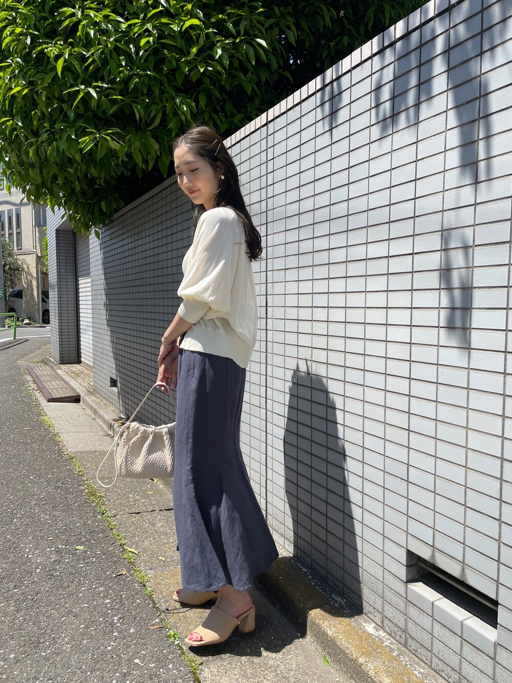 ブルー系のスカート、ホワイト系のカーディガン/ボレロ、ホワイト系のニット/セーターを着用したレディースの春コーディネートの2枚目の写真