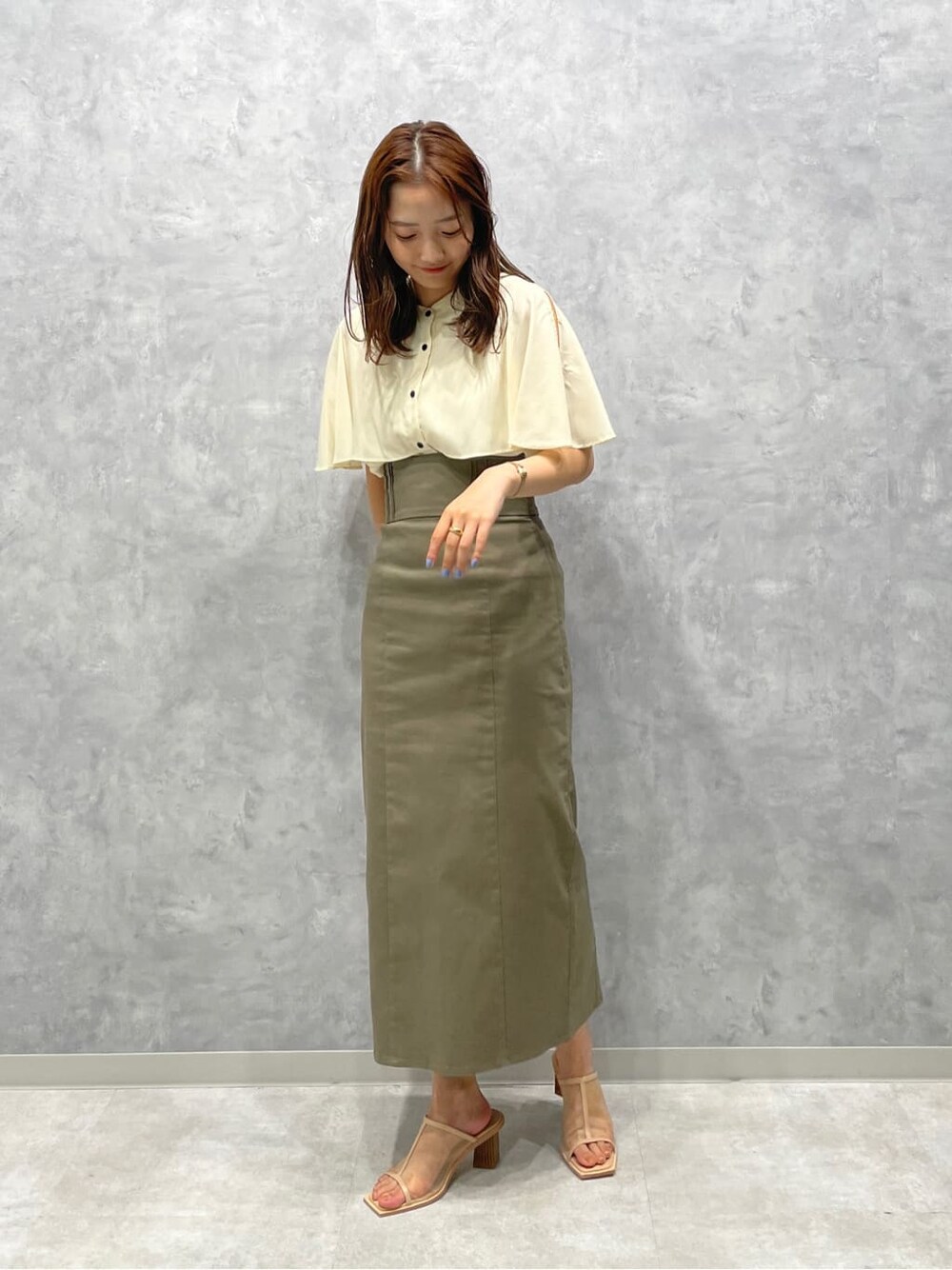 ベージュ系のスカート、ベージュ系のサンダル、ホワイト系のシャツ/ブラウスを着用したレディースの夏コーディネートの2枚目の写真