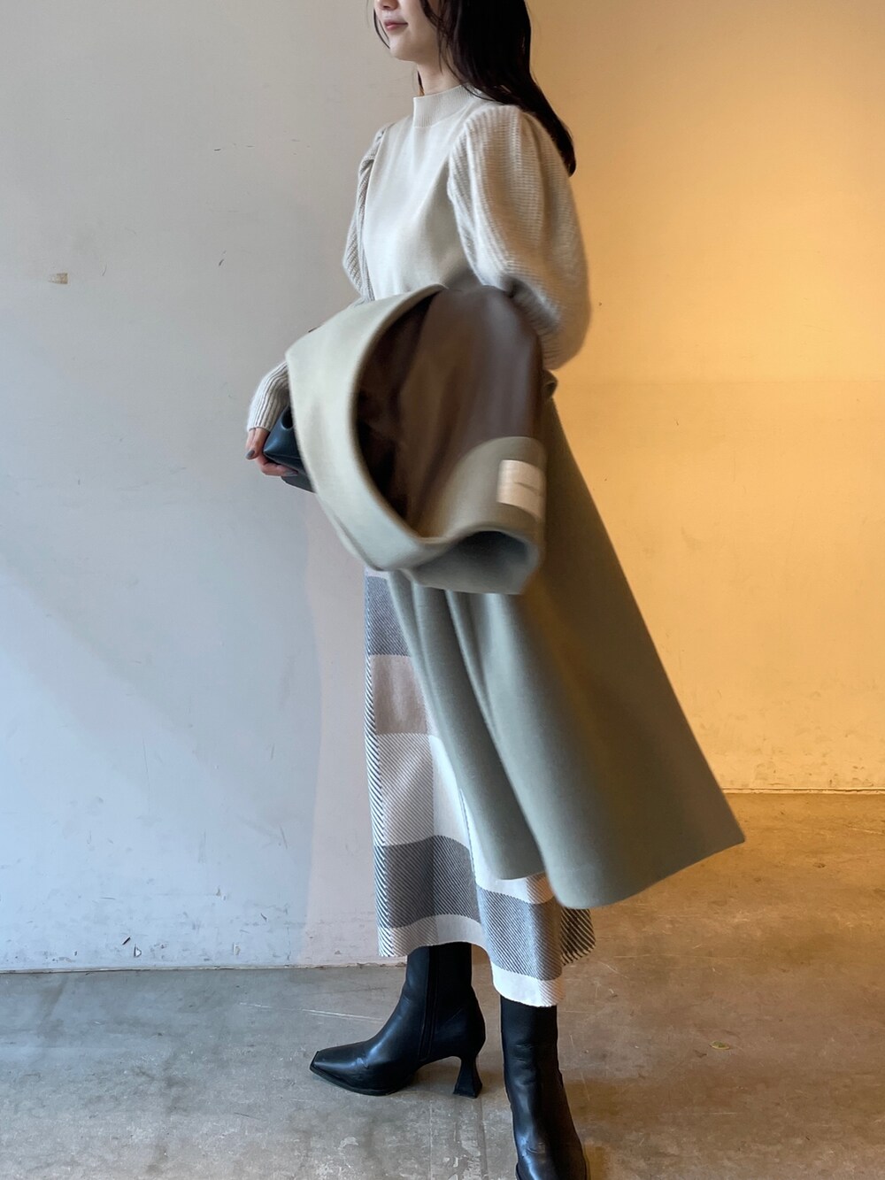 ブラック系のブーツ、ベージュ系のスカート、ホワイト系のニット/セーターを着用したレディースの冬コーディネートの3枚目の写真