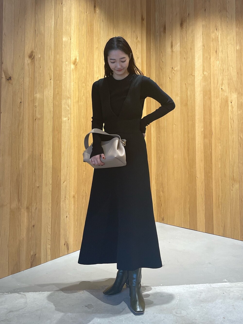 ベージュ系のハンドバッグ、グリーン系のブーツ、ブラック系のスカートを着用したレディースの秋コーディネートの3枚目の写真