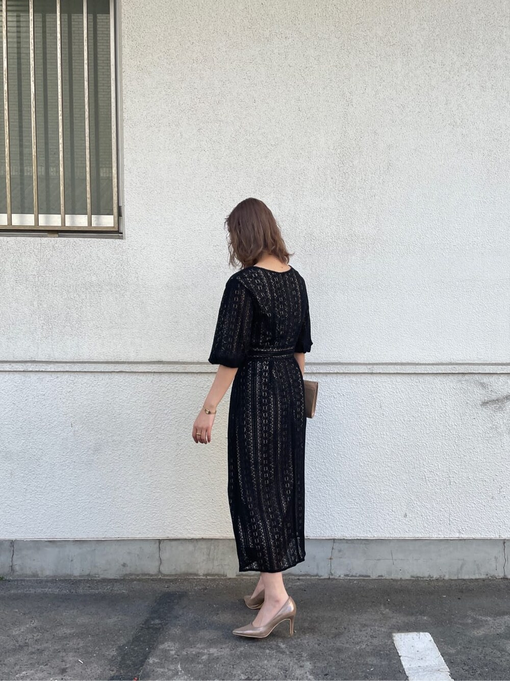 ゴールド系のパンプス、ゴールド系のクラッチバッグ、ブラック系のドレスを着用したレディースの冬コーディネートの3枚目の写真