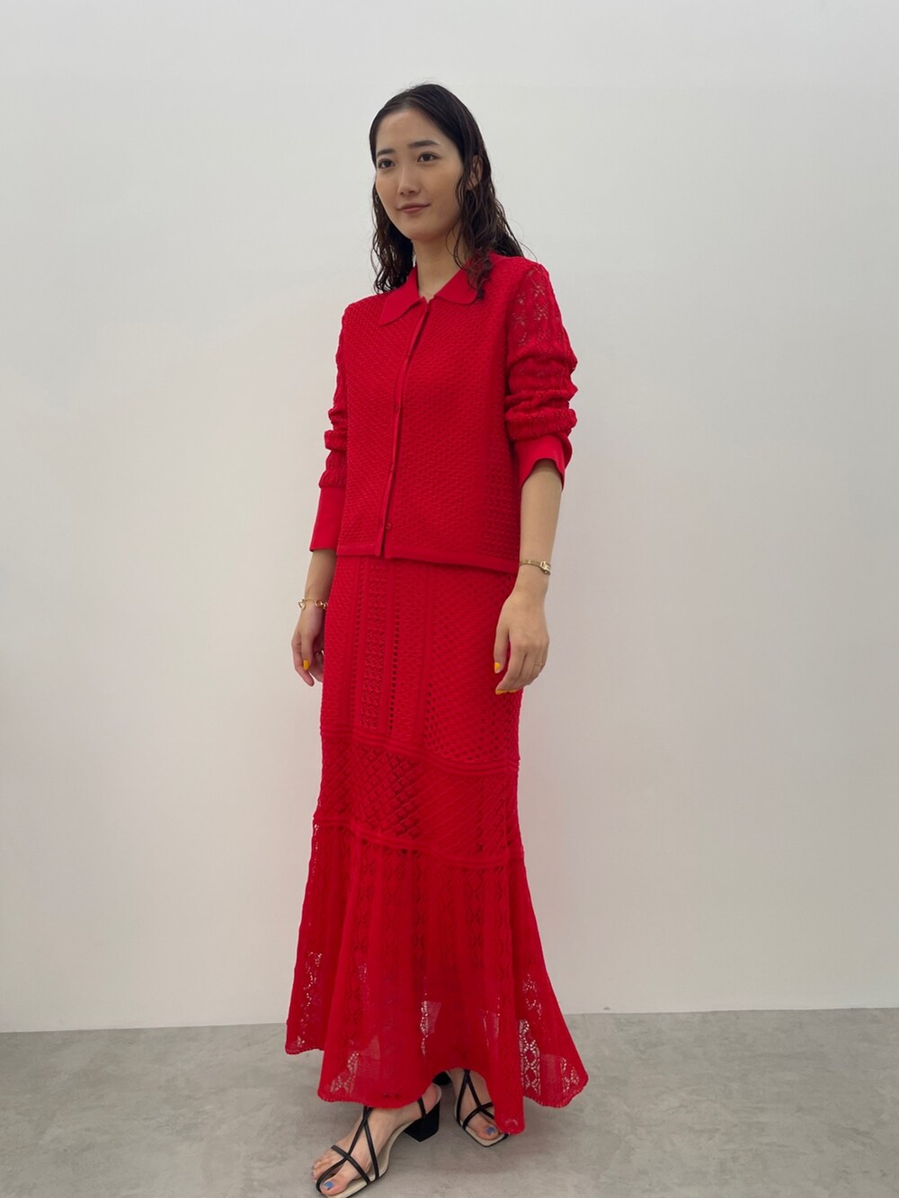 レッド系のカーディガン/ボレロ、レッド系のスカート、ブラック系のサンダルを着用したレディースの春コーディネートの5枚目の写真