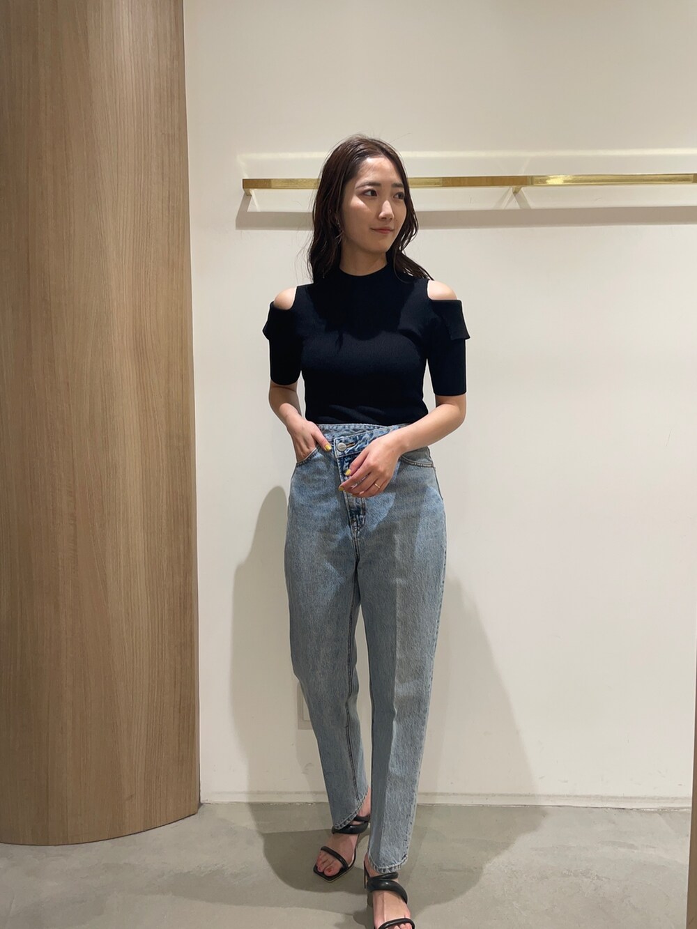 ブラック系のニット/セーター、ブラック系のサンダル、ブルー系のデニムパンツを着用したレディースの春コーディネートの2枚目の写真