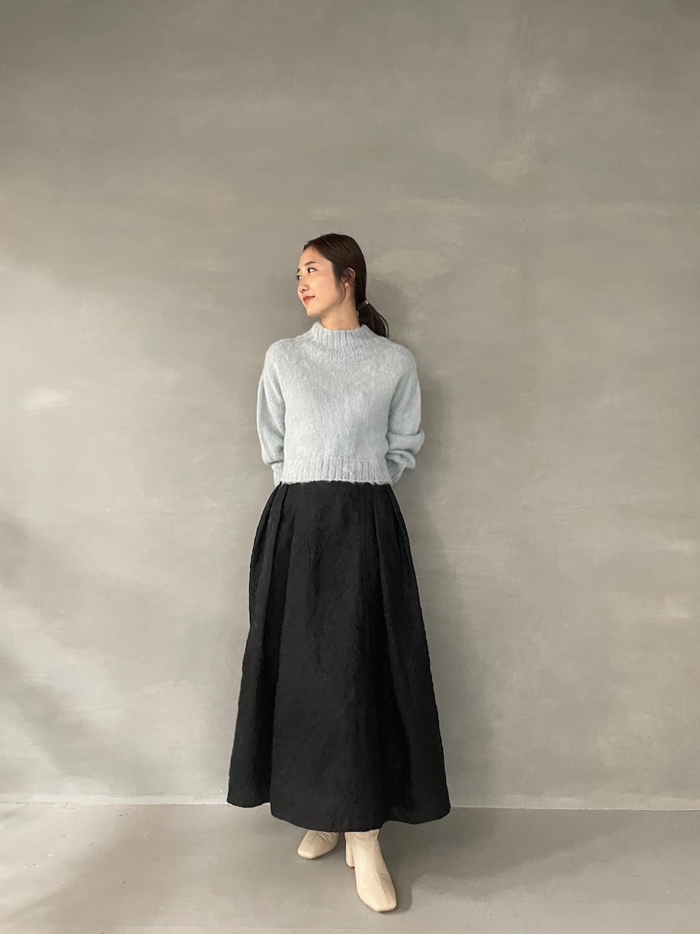 ホワイト系のブーツ、ブラック系のスカート、グリーン系のニット/セーターを着用したレディースの夏コーディネートの2枚目の写真