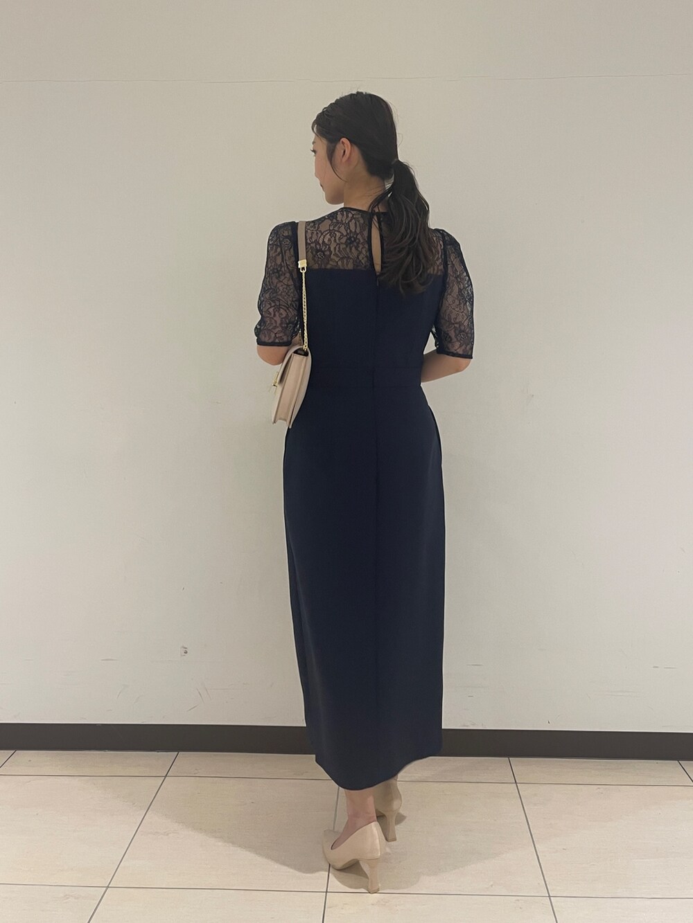 ゴールド系のクラッチバッグ、ベージュ系のパンプス、ブルー系のドレスを着用したレディースの春コーディネートの6枚目の写真