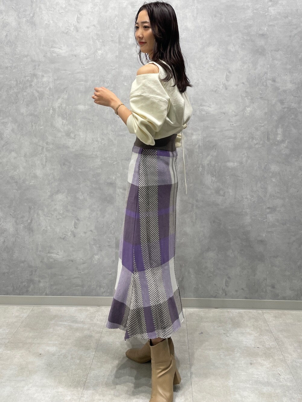 ベージュ系のブーツ、ホワイト系のニット/セーター、パープル系のスカートを着用したレディースの冬コーディネートの5枚目の写真