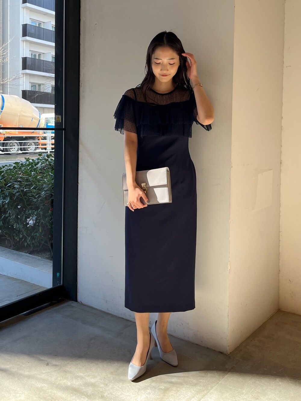 グレー系のパンプス、グレー系のクラッチバッグ、ブルー系のドレスを着用したレディースの冬コーディネートの2枚目の写真