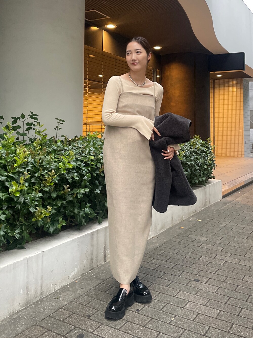 ベージュ系のワンピース、ホワイト系のニット/セーター、ブラック系のローファーを着用したレディースの秋コーディネートの2枚目の写真