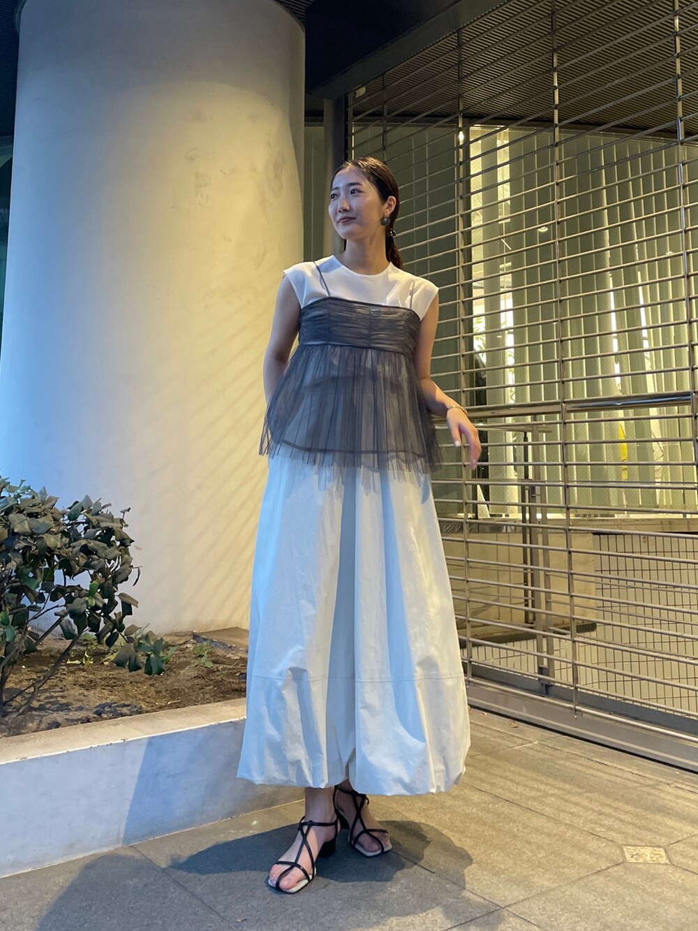 グレー系のTシャツ/カットソー、ホワイト系のスカート、ブラック系のサンダルを着用したレディースの春コーディネートの2枚目の写真