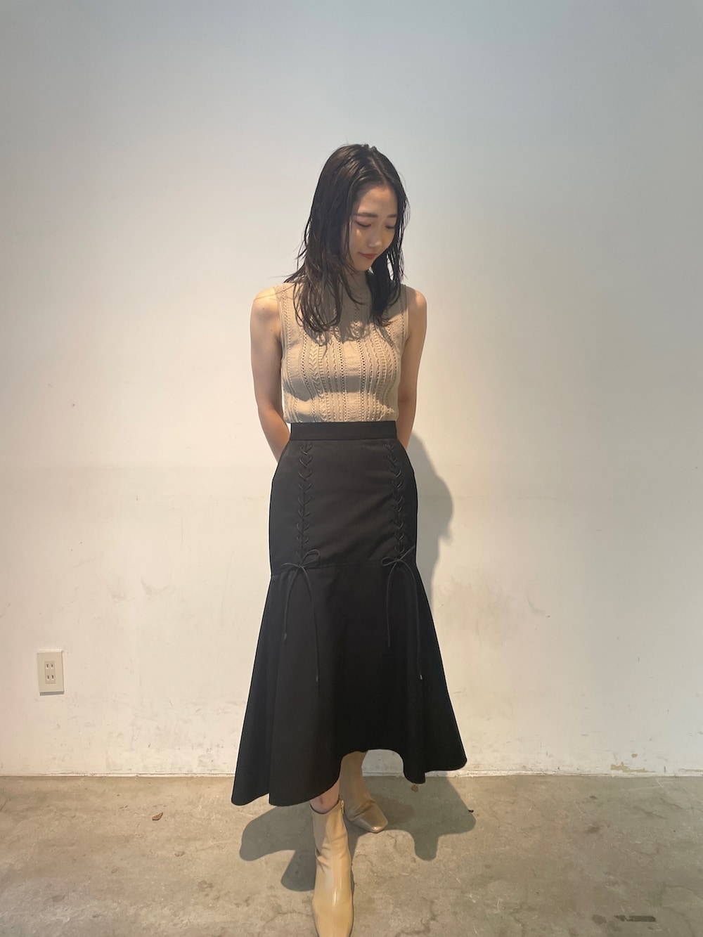 ベージュ系のニット/セーター、ベージュ系のブーツ、ブラック系のスカートを着用したレディースの夏コーディネートの2枚目の写真