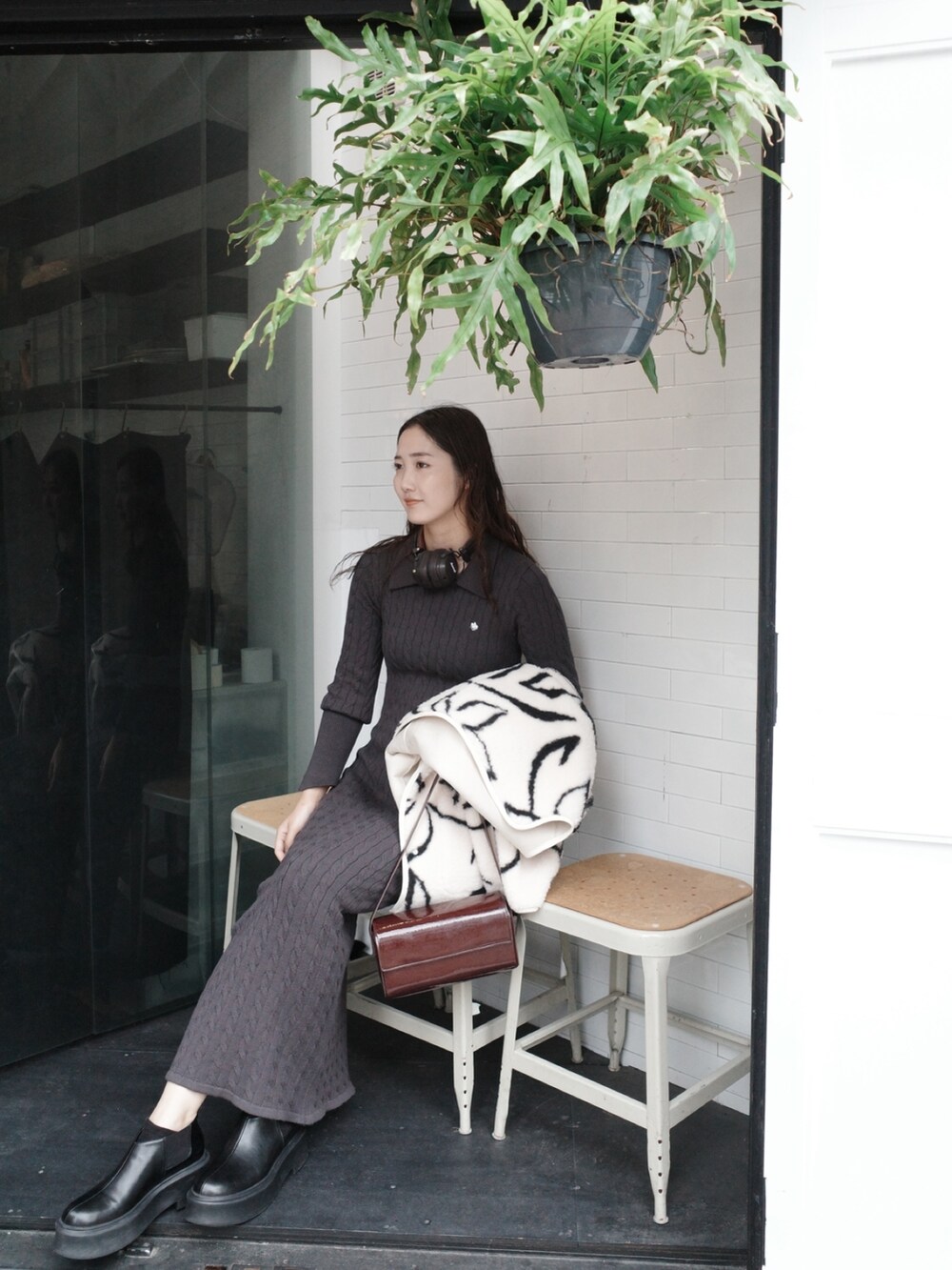 グレー系のワンピース、ホワイト系のブルゾン、ブラック系のブーツを着用したレディースの夏コーディネートの3枚目の写真