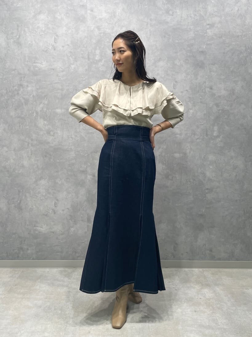 ベージュ系のブーツ、ブルー系のスカート、ホワイト系のニット/セーターを着用したレディースの秋コーディネートの2枚目の写真