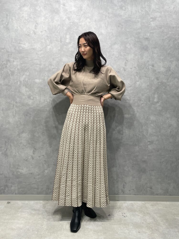 ホワイト系のノーカラーコート、ブラック系のブーツ、ベージュ系のワンピースを着用したレディースの秋コーディネートの4枚目の写真