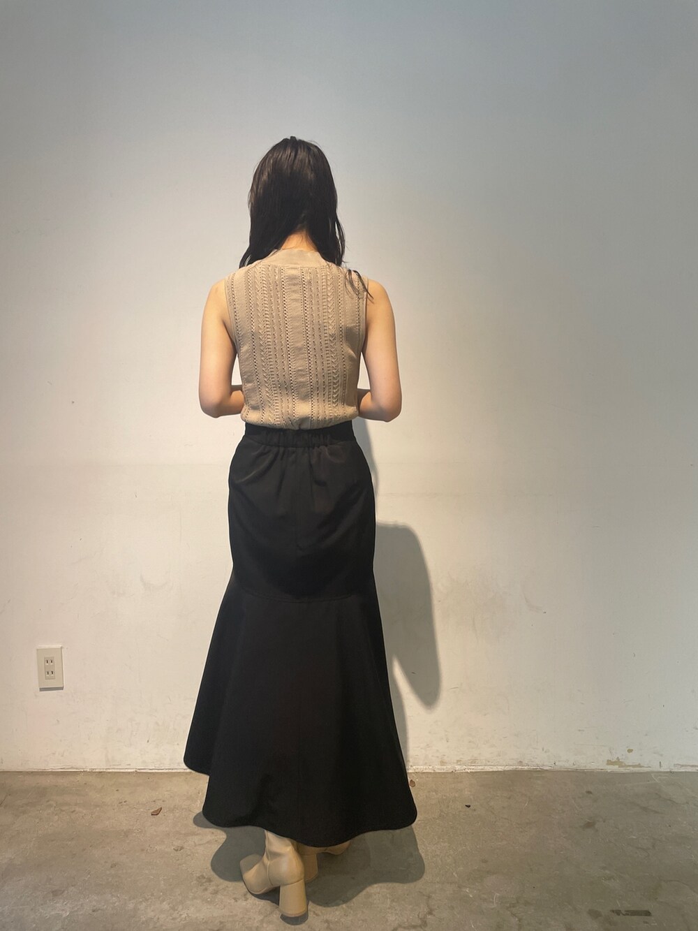 ベージュ系のニット/セーター、ベージュ系のブーツ、ブラック系のスカートを着用したレディースの夏コーディネートの6枚目の写真