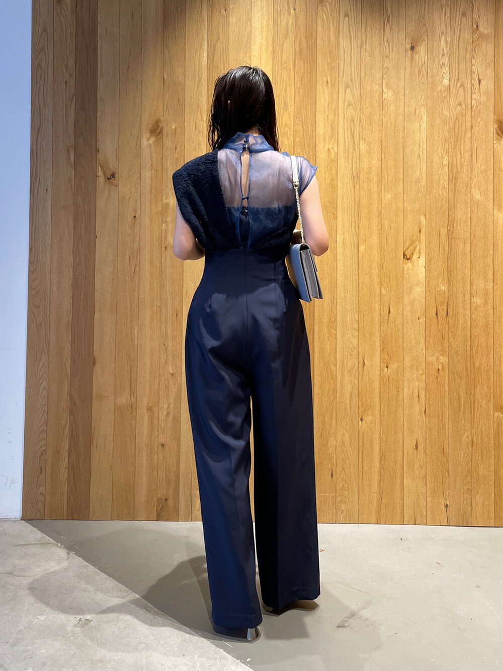 グレー系のクラッチバッグ、グレー系のパンプス、ブルー系のパンツドレスを着用したレディースの冬コーディネートの5枚目の写真