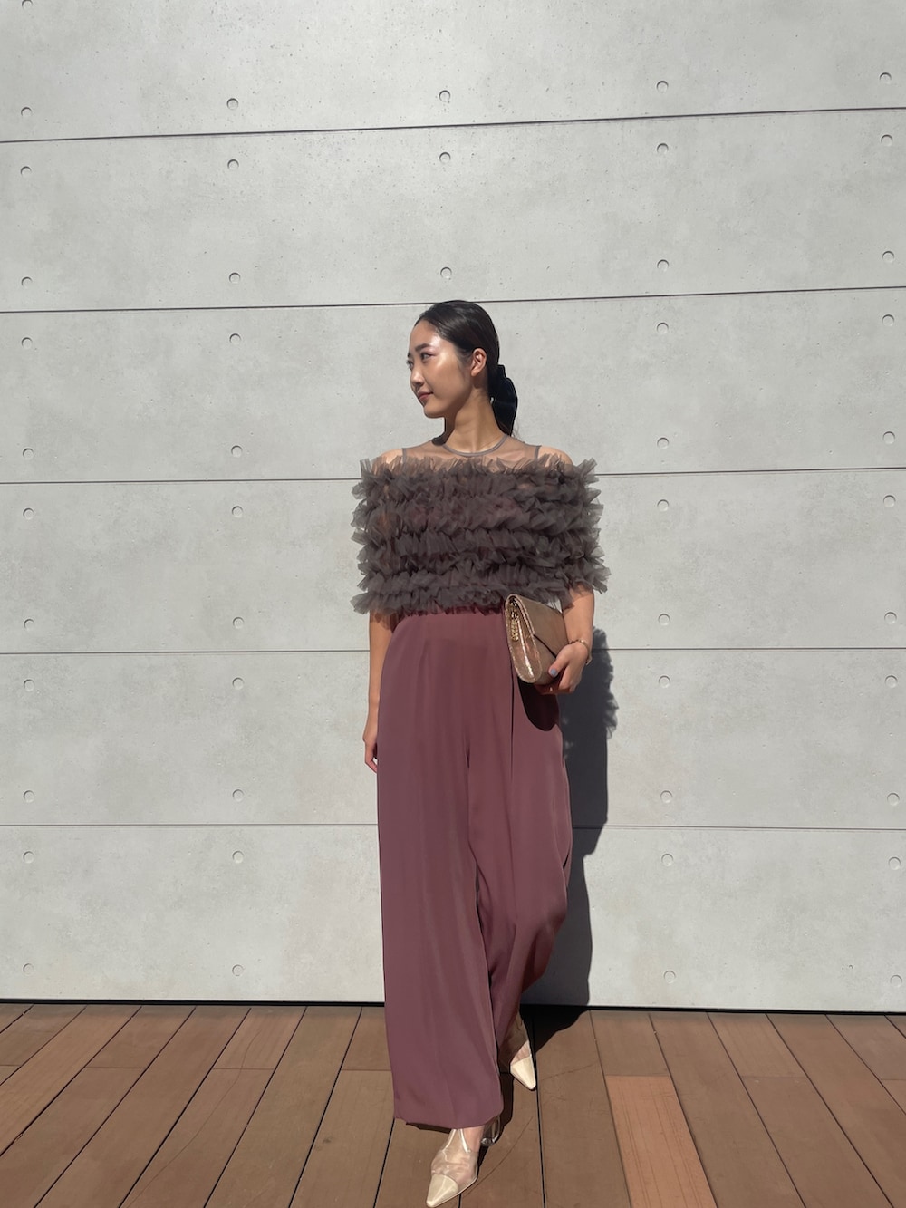 ピンク系のパンツドレス、ゴールド系のハンドバッグ、ベージュ系のパンプスを着用したレディースの秋コーディネートの2枚目の写真