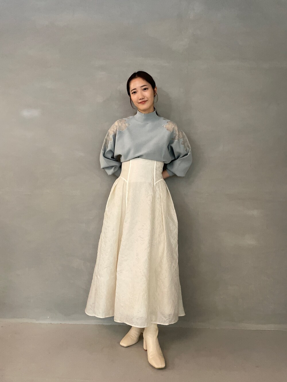 グレー系のニット/セーター、ホワイト系のスカート、ホワイト系のブーツを着用したレディースの夏コーディネートの3枚目の写真