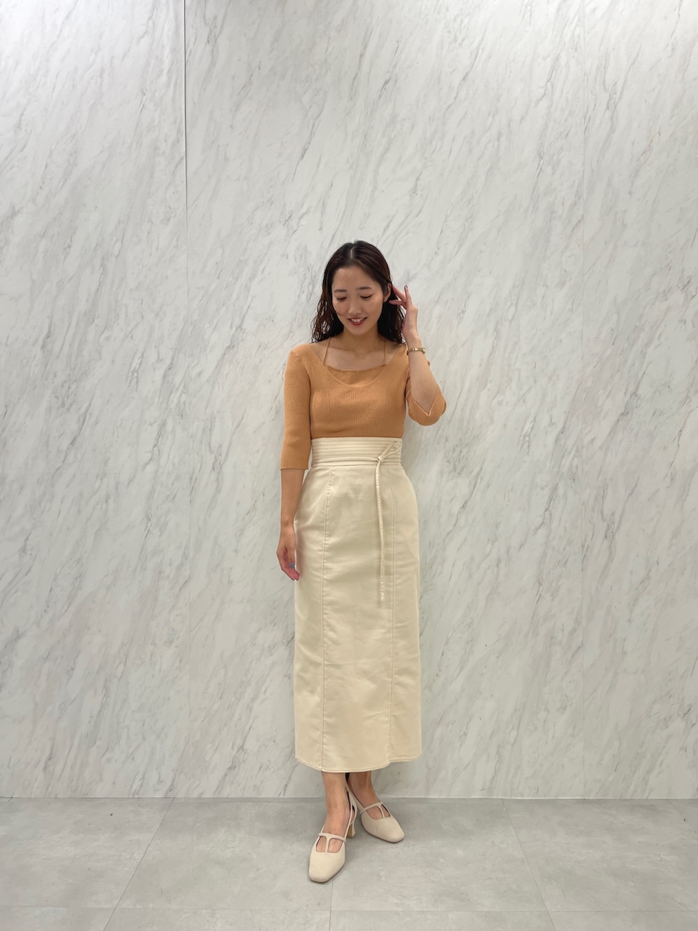 ホワイト系のパンプス、オレンジ系のニット/セーター、ホワイト系のスカートを着用したレディースの冬コーディネートの2枚目の写真