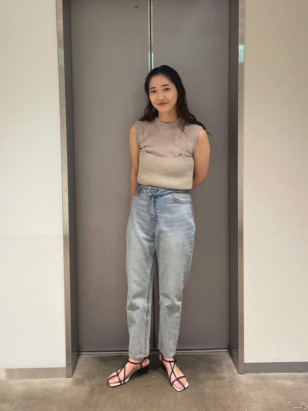 ブルー系のデニムパンツ、ベージュ系のニット/セーター、ブラック系のサンダルを着用したレディースの春コーディネートの4枚目の写真