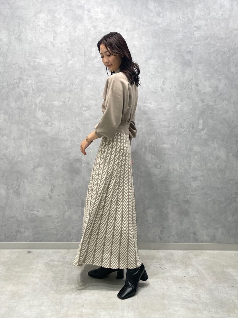 ホワイト系のノーカラーコート、ブラック系のブーツ、ベージュ系のワンピースを着用したレディースの秋コーディネートの5枚目の写真