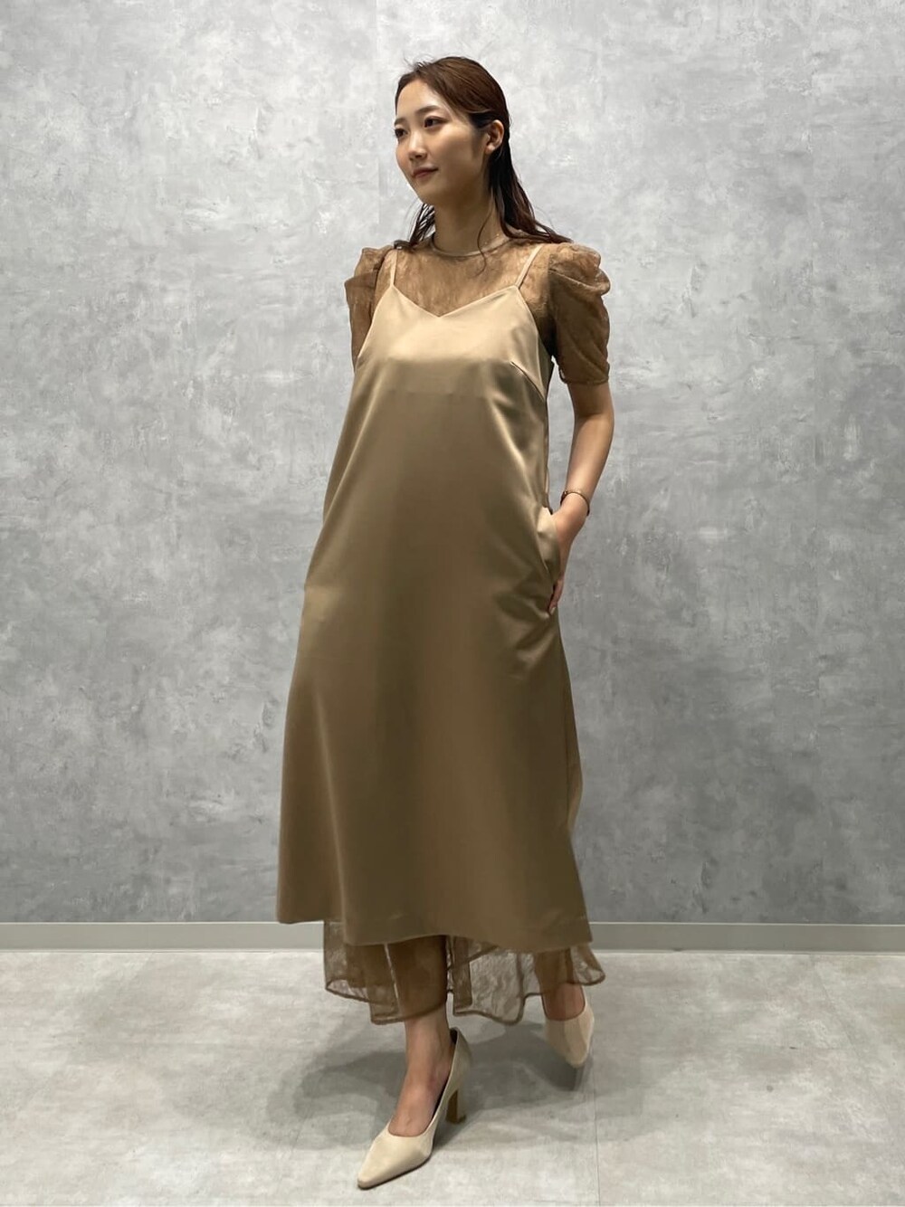 ゴールド系のクラッチバッグ、ベージュ系のパンプス、ベージュ系のドレスを着用したレディースの春コーディネートの3枚目の写真