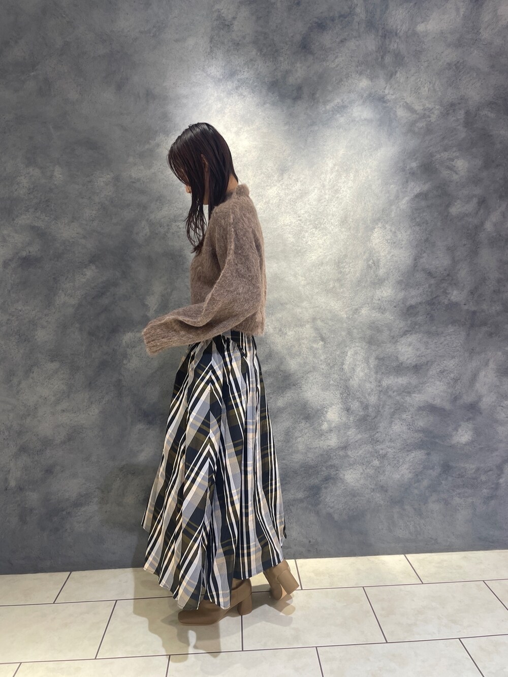 ブラウン系のニット/セーター、オレンジ系のスカート、ベージュ系のブーツを着用したレディースの秋コーディネートの6枚目の写真