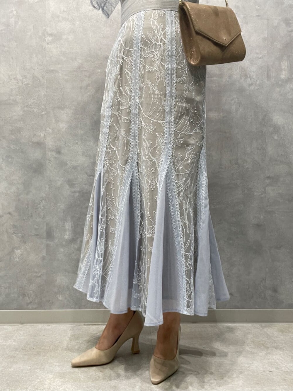 ゴールド系のクラッチバッグ、ベージュ系のパンプス、ブルー系のドレスを着用したレディースの春コーディネートの9枚目の写真