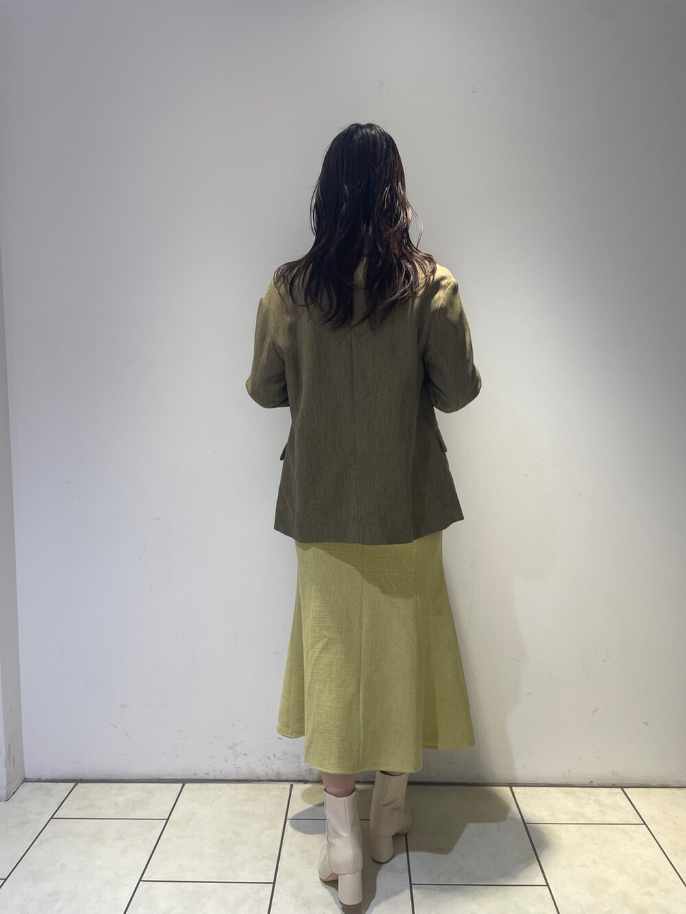 イエロー系のワンピース、ホワイト系のブーツ、ブラウン系のテーラードジャケットを着用したレディースの秋コーディネートの5枚目の写真