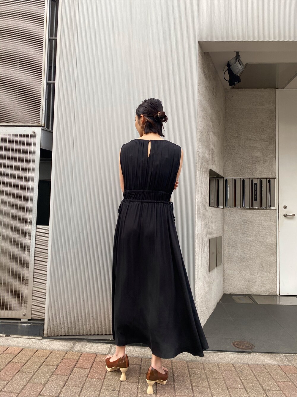 ブラウン系のパンプス、グレー系のカーディガン/ボレロ、ブラック系のワンピースを着用したレディースの春コーディネートの6枚目の写真