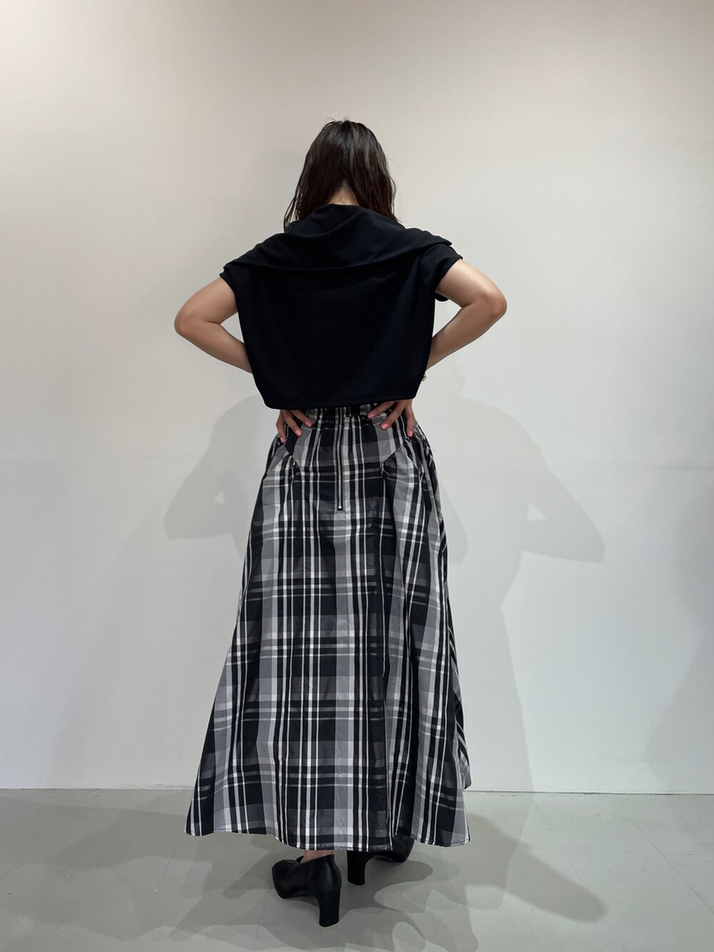 ブラック系のTシャツ/カットソー、ブラック系のパンプス、ホワイト系のスカートを着用したレディースの夏コーディネートの6枚目の写真