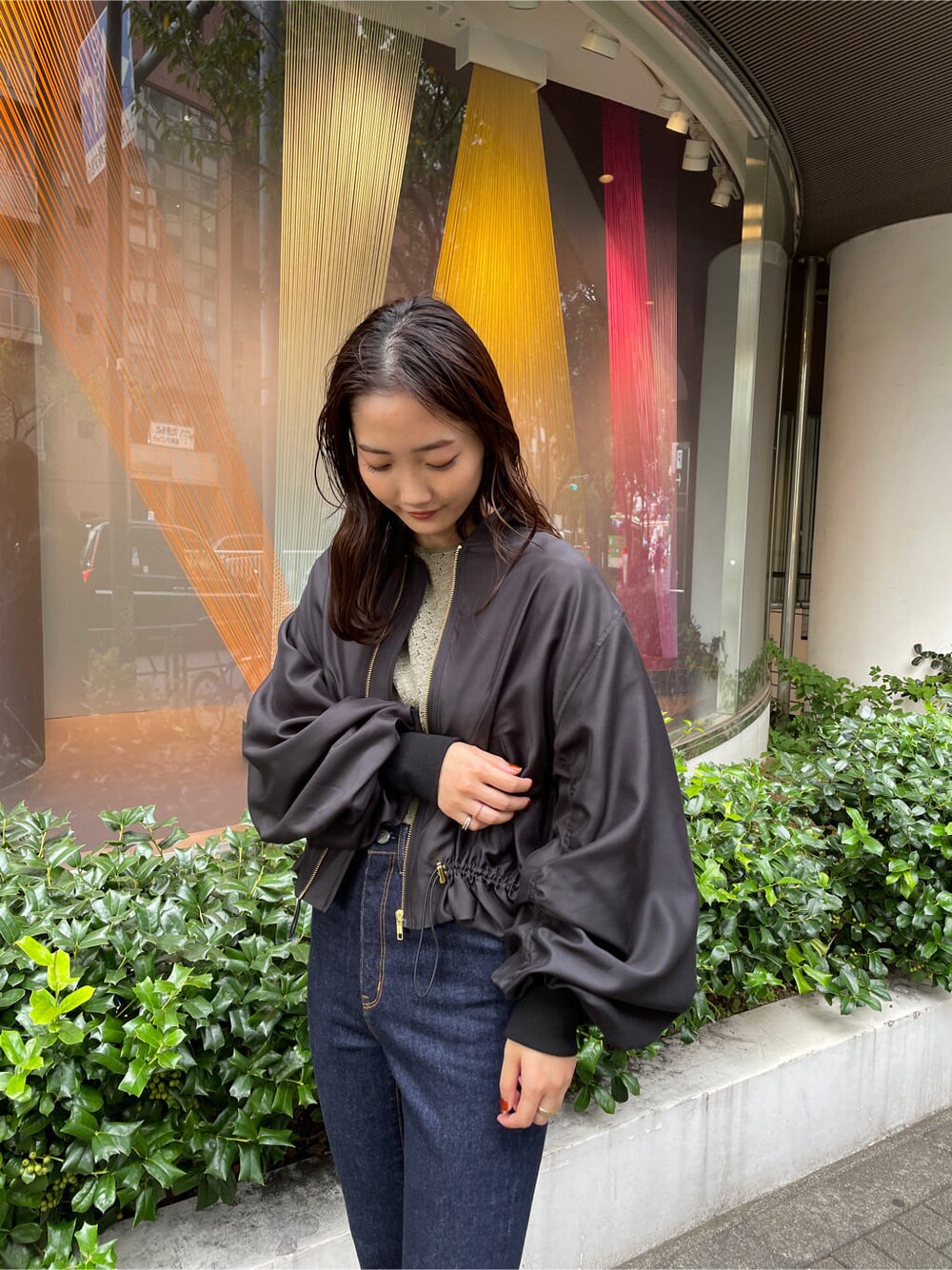 ベージュ系のシャツ/ブラウス、ブラック系のブルゾン、ブルー系のデニムパンツを着用したレディースの秋コーディネートの4枚目の写真