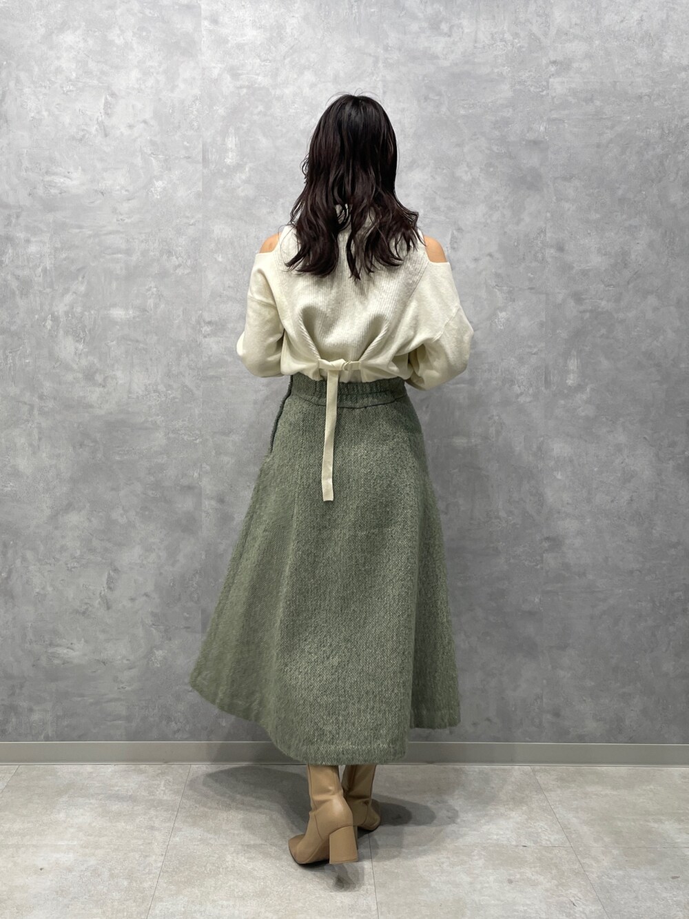 ベージュ系のブーツ、ホワイト系のニット/セーター、グリーン系のスカートを着用したレディースの冬コーディネートの6枚目の写真