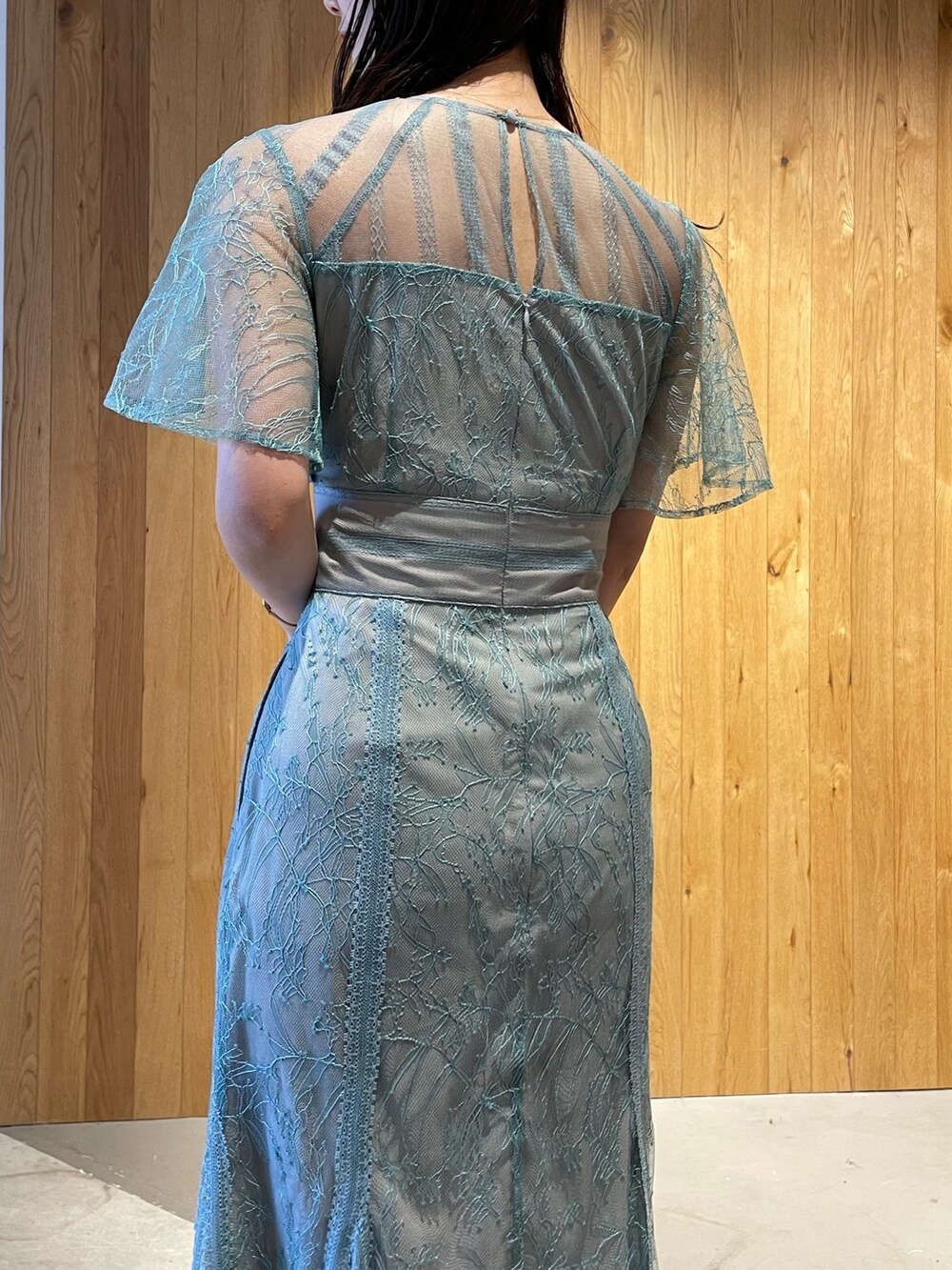 グレー系のクラッチバッグ、グレー系のパンプス、グリーン系のドレスを着用したレディースの冬コーディネートの6枚目の写真