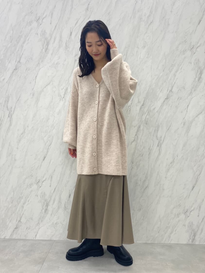 ブラック系のブーツ、ベージュ系のスカート、ホワイト系のカーディガン/ボレロを着用したレディースの秋コーディネートの2枚目の写真