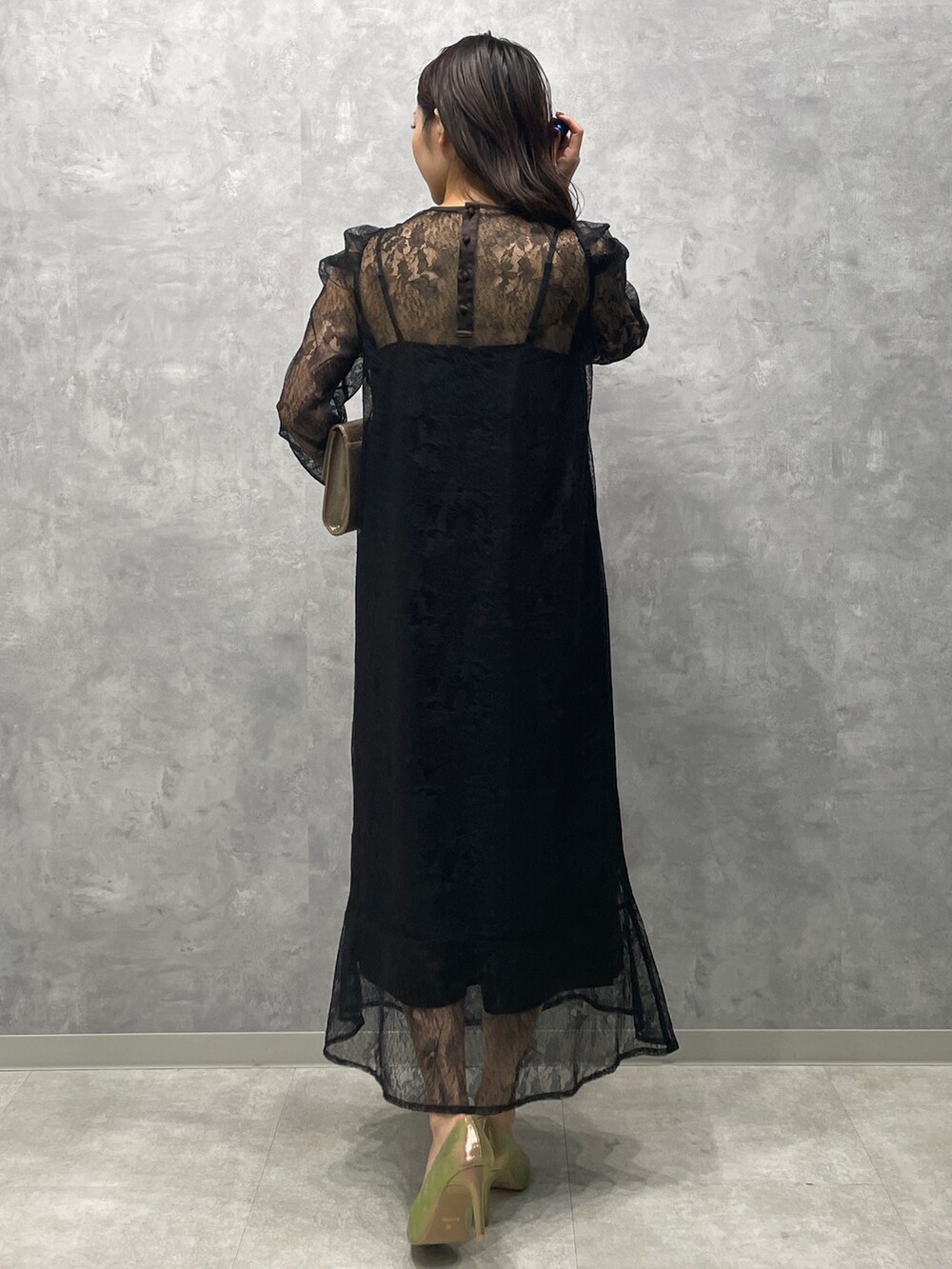 ゴールド系のパンプス、ゴールド系のハンドバッグ、ブラック系のドレスを着用したレディースの秋コーディネートの5枚目の写真