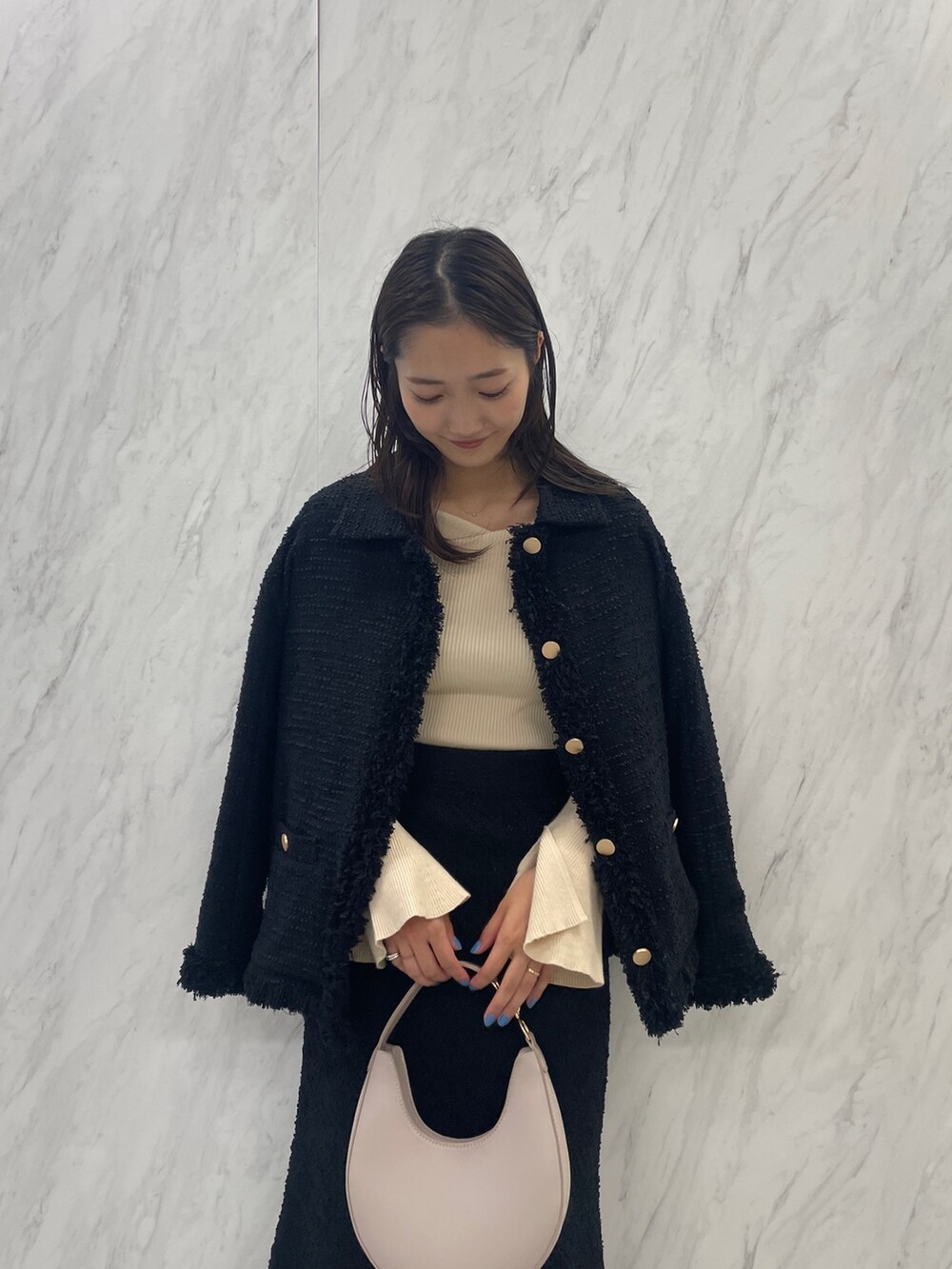 ブラック系のブーツ、ホワイト系のハンドバッグ、ブラック系のスカートを着用したレディースの秋コーディネートの6枚目の写真