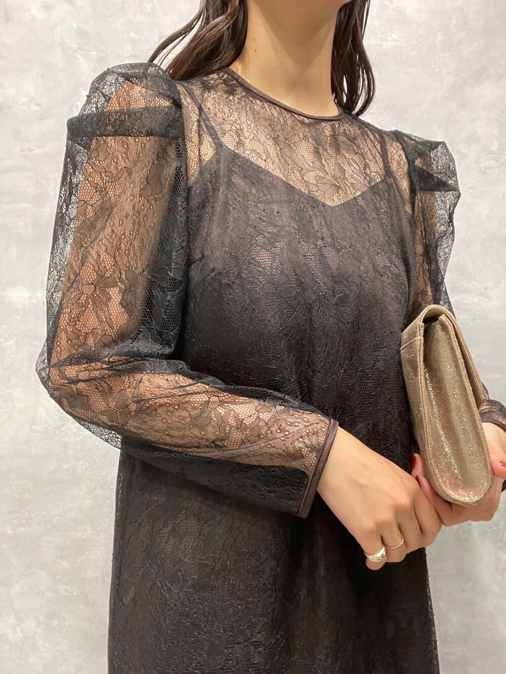 ゴールド系のパンプス、ゴールド系のハンドバッグ、ブラック系のドレスを着用したレディースの秋コーディネートの6枚目の写真