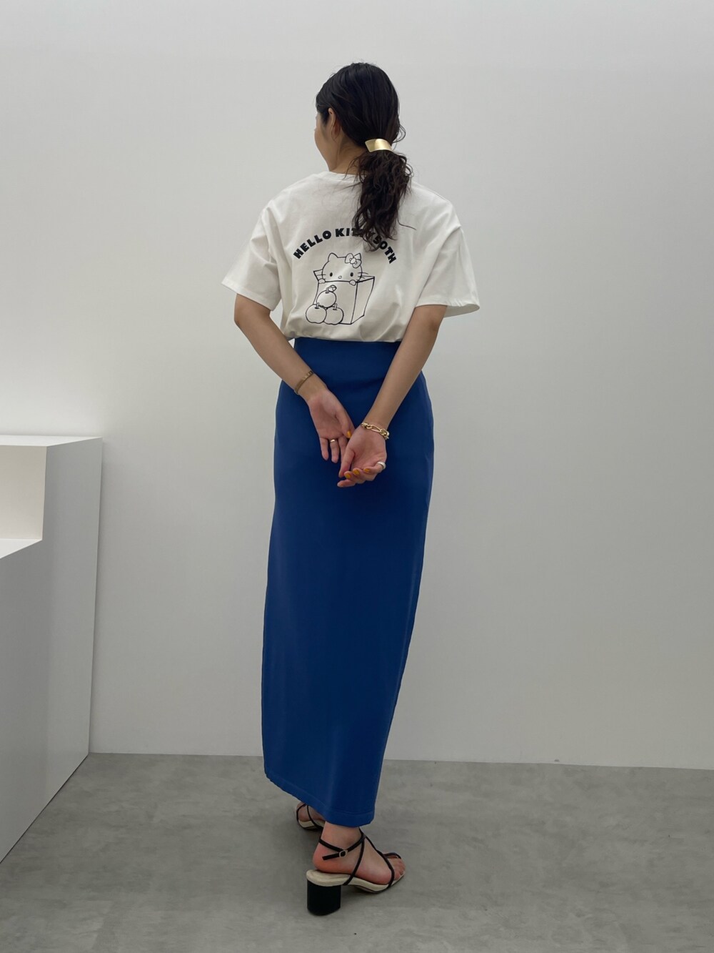 ブルー系のスカート、ホワイト系のTシャツ/カットソー、ブラック系のサンダルを着用したレディースの春コーディネートの6枚目の写真