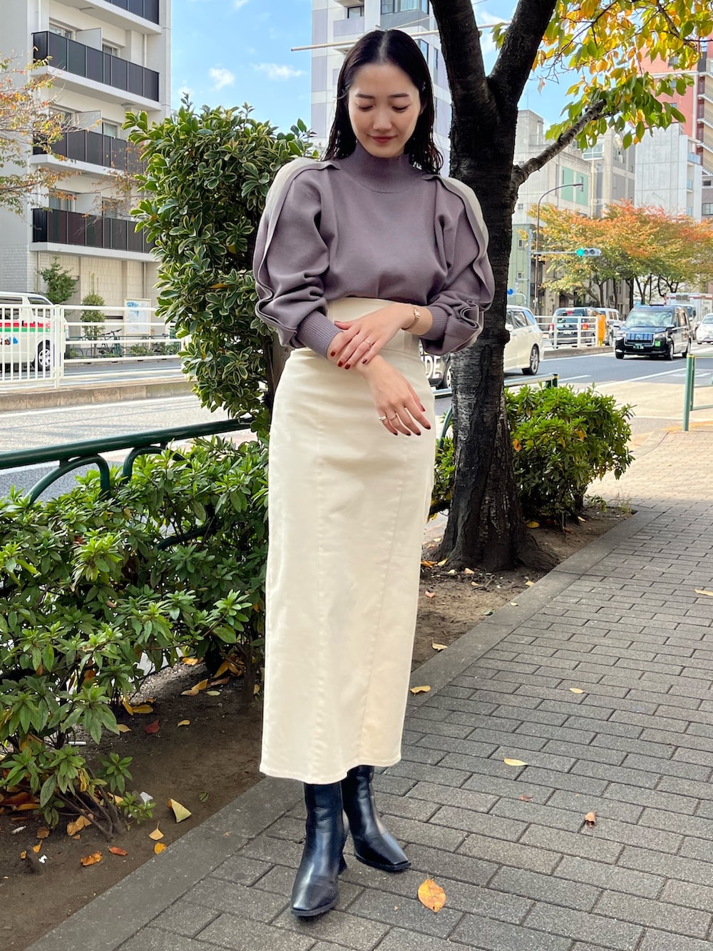 ブラック系のブーツ、ホワイト系のスカート、ベージュ系のニット/セーターを着用したレディースの冬コーディネートの3枚目の写真