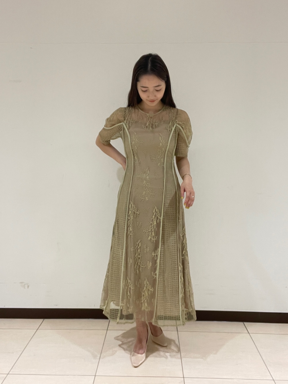 ベージュ系のパンプス、グリーン系のドレスを着用したレディースの春コーディネートの3枚目の写真