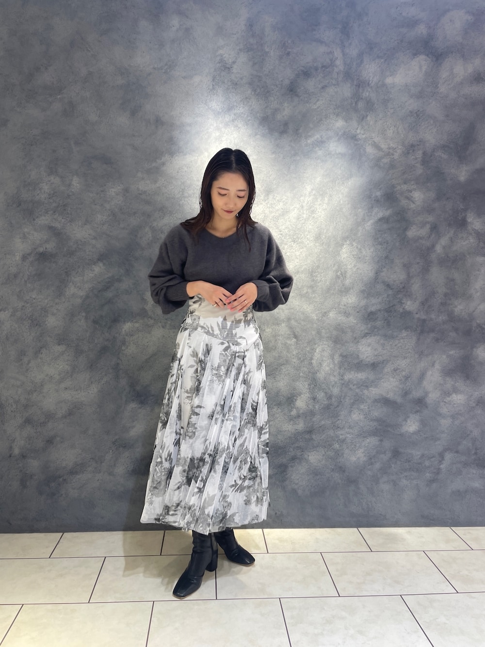 ブラック系のスカート、ブラック系のブーツ、グレー系のニット/セーターを着用したレディースの秋コーディネートの3枚目の写真