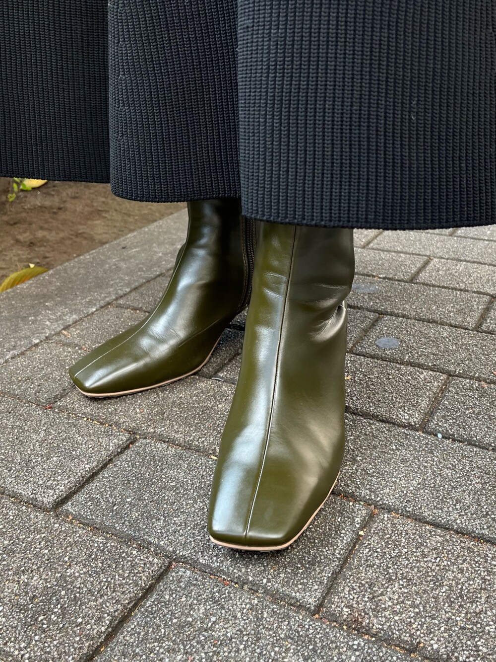 ベージュ系のハンドバッグ、グリーン系のブーツ、ブラック系のスカートを着用したレディースの秋コーディネートの8枚目の写真